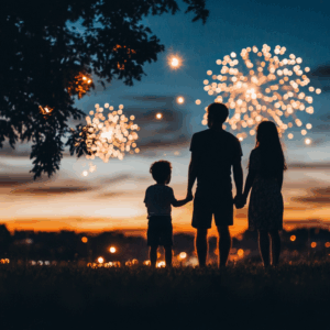 Family holding hands while watching a fireworks display.